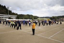 グラウンドで、参加者が上体を反らして手を広げている写真