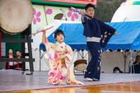 ステージの上で着物姿の男性と女性が、扇子を持って踊っている写真