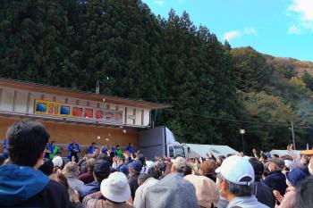 大勢の参加者が集まるまつりの会場で餅まきが行われている写真