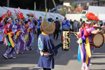 色とりどりの衣装を着た人々がまつりの会場で踊りを披露している写真
