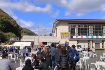 長い行列の後ろで男性がタイムサービス最後尾と書かれた手持ち看板を持っている写真