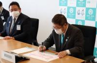 手前の男性がサインをしている様子を奥の男性がみている写真