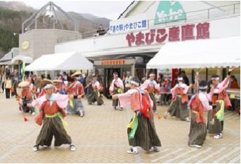 道の駅やまびこ館の建物前で、和装をした人たちが踊っている写真