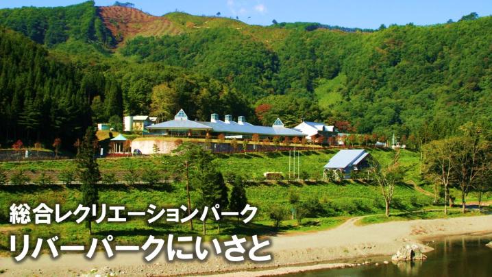 総合レクレーションパーク リバーパークにいさとの文字と山に囲まれたリバーパークにいさとの外観写真