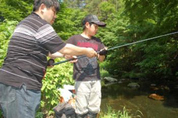 男の子と男性が1本の釣り竿を一緒に持って魚釣りをしている様子の写真