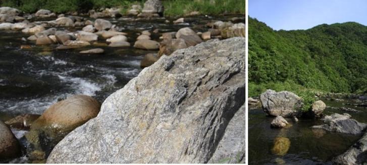 ゴツゴツとした石を拡大した写真、緑に囲まれ、流れる川の途中に大小の石がある写真