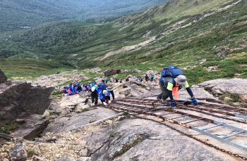 急斜面の場所を梯子を使い登山者の方々が上っている様子を写した写真