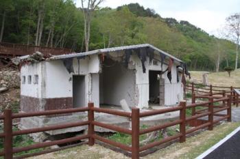 屋根や一部が崩れ、建物の外観の形は残っているトイレの写真