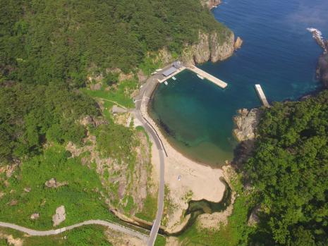 山に囲まれた海沿いの沿岸部にある姉吉地区の港を上空から写した写真
