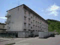 緑に囲まれ、駐輪場や野外物置が設置された4階建て集合住宅(1棟)の外観写真
