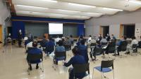 パイプ椅子に座り重茂漁協の室内で説明会に参加している人達を後ろから写した写真