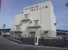 道路沿いに建つ白い外観の新川町雨水ポンプ場の写真