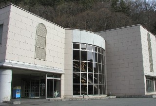 三つの異なる形の建物が一つの建物として建築されている。真ん中の建物はガラス張りでうっすら螺旋階段が見えている写真
