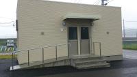 入口正面に3段ほどの段差があり隣に手すり付きのスロープが設置されている更衣室の外観写真