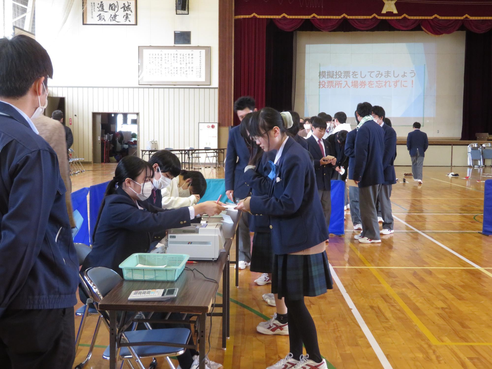 高校生スタッフが投票用紙を交付している写真