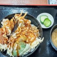 トレーの上にきゅうりのお漬物と味噌汁、ご飯が見えないくらい上からタレがかかった天ぷらが盛り付けられた宮古天丼をアップで撮影した写真