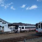 側面に白地に赤ラインで模様が描かれた観光列車「ひなび(陽旅)」が停車している様子を正面から撮影した写真