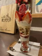 木製のトレイの上にカットされたイチゴや生クリームなどで盛り付けられたパフェの写真