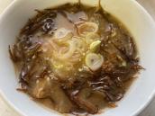 湯がいて味付けされた海藻の上に輪切りにカットされたネギが添えられている料理の写真