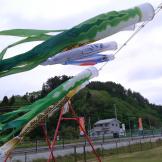 キッズパークに設置されたロープウェイの傍で、風に吹かれて泳いでいる「鮭のぼり」や真崎わかめの吹き流しの写真