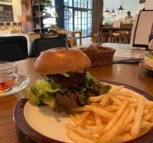 お皿に盛られたフライドポテトとレタスや具材がパンからはみ出すほどの大きさのハンバーガーの写真