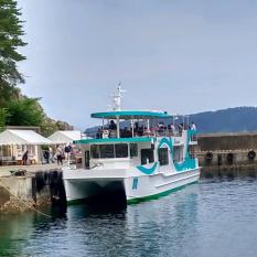 船乗り場に停泊した、白い船体にエメラルドグリーン色のラインがデザインされた浄土ヶ浜遊覧船の写真