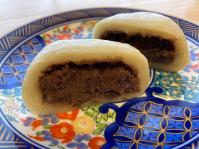 半分にカットされ中に餡子がびっしり詰まった饅頭が断面が見えるように花柄の青色の丸皿に置かれた写真