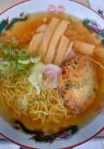 ラーメンどんぶりに入った透明の澄んだうす茶色のスープの中に麺とメンマ、輪切りにカットされたネギや揚げものがトッピングされた宮古ラーメンを上から撮影した写真