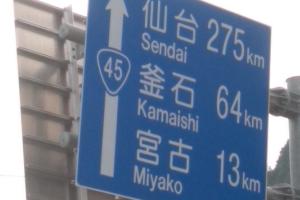 道路の青い看板で下から、宮古13キロメートル、釜石64キロメートル、仙台275キロメートルと描かれている写真