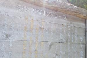 上部に伝説義経北行コースと書かれた木の看板に、詳細な内容が書かれている写真