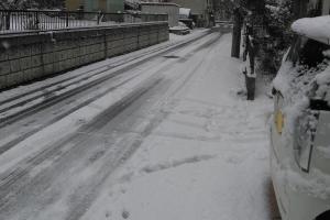 薄っすらと雪が積もっている市街地の道路の写真
