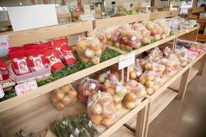 木製の棚に野菜やリンゴチップスなどが陳列されている写真