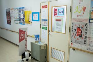 ジョブカフェみやこと書かれた看板が置かれた、両脇や入口に仕事に関するポスターが貼られている室内の扉の写真