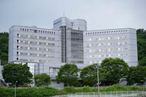 青々とした木々に囲まれた、白い外観で複数階建ての県立宮古病院の写真