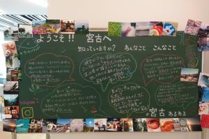 「ようこそ!!宮古へ」という文字や宮古の豆知識やあるあるなどのコメントが書かれた黒板と、その枠に貼り付けられている特産品や景色などの写真