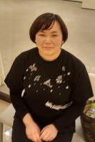 椅子に座ってほほえむ女性を正面から写した写真