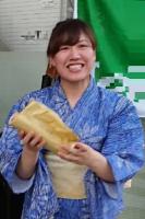 浴衣を着て両手で物を持ちながら笑う女性を正面から写した写真