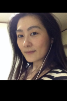 両耳にイヤホンをつけてほほえむ女性を斜め前から写した写真