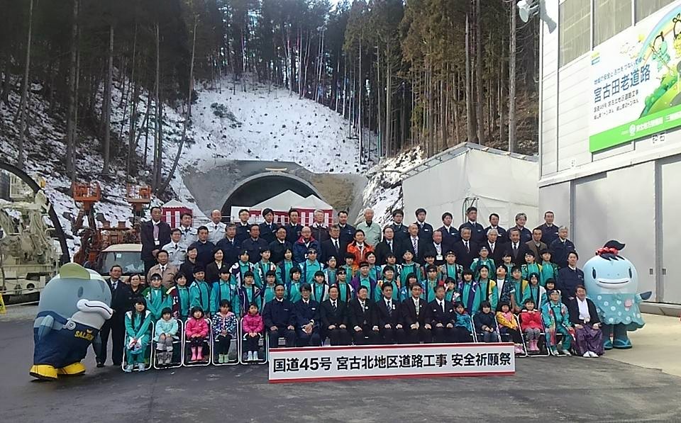 トンネルの前で並ぶ関係者や子供たち、サーモンくんとみやこちゃんの記念写真