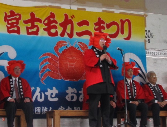 カニの被り物を被った市長がマイクを持ち話をしている様子の写真