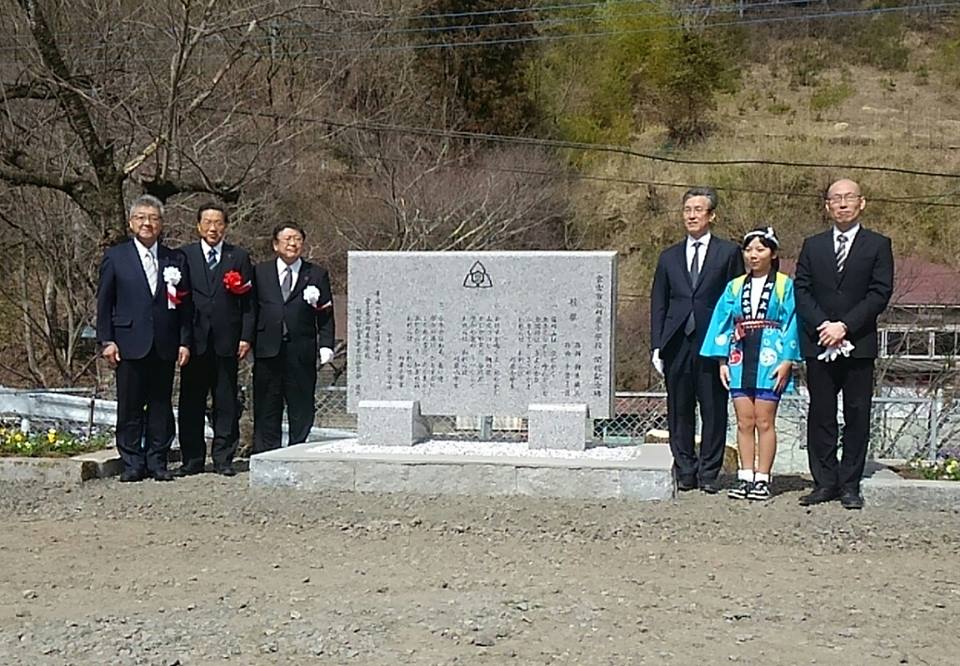 石碑の左側に立つ市長と男性2名、右側に立つ法被を着た女の子と男性2名の記念写真