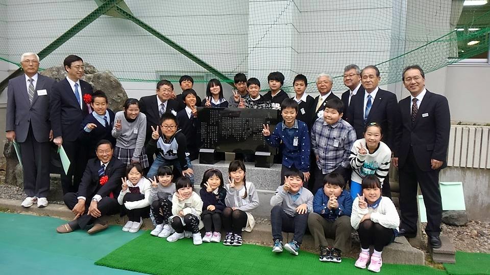 石碑の周りに集まって、ピースサインをする子供たちと関係者の方々の記念写真