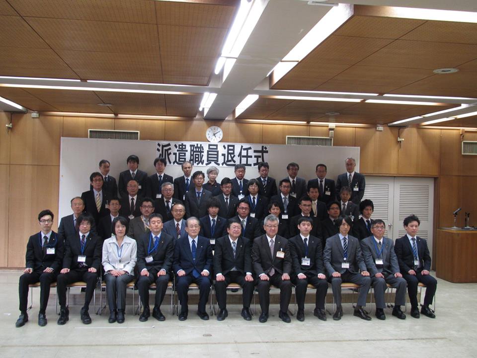 「派遣職員退任式」と書かれたパネルの前で4列に整列する市長や派遣職員の方々の記念写真