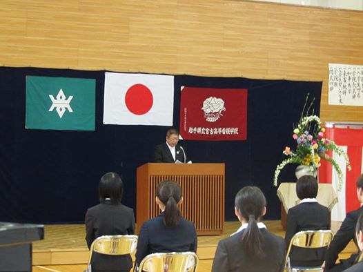 前の演台で祝辞を述べている市長と座って聞いている新入生の写真