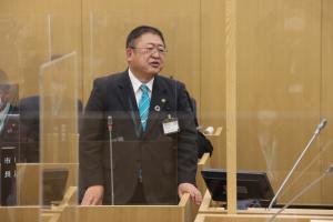 市議会議場の演壇に立ち、発言している市長の写真