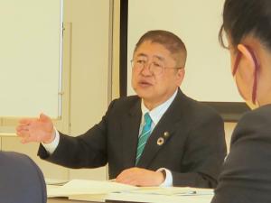 机に資料を置き、ジェスチャーを交えながら話をする市長の写真