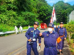 活動服を着た市長と男性が道路脇を歩いている写真