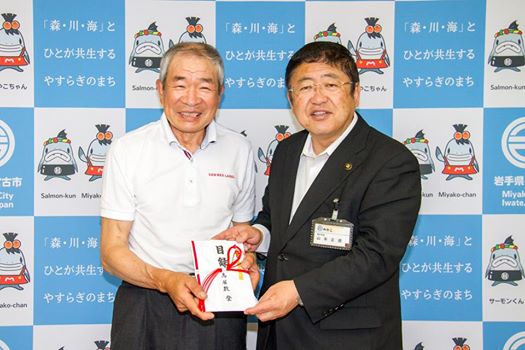 バックパネルの前で目録を一緒に持つ市長と男性の記念写真