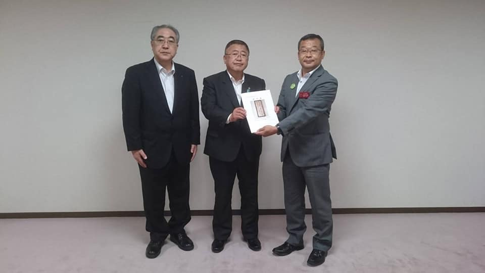 要望書を一緒に持つ市長と灰色のスーツを着た男性、黒いスーツを着た男性1名が横一列に並んでいる記念写真