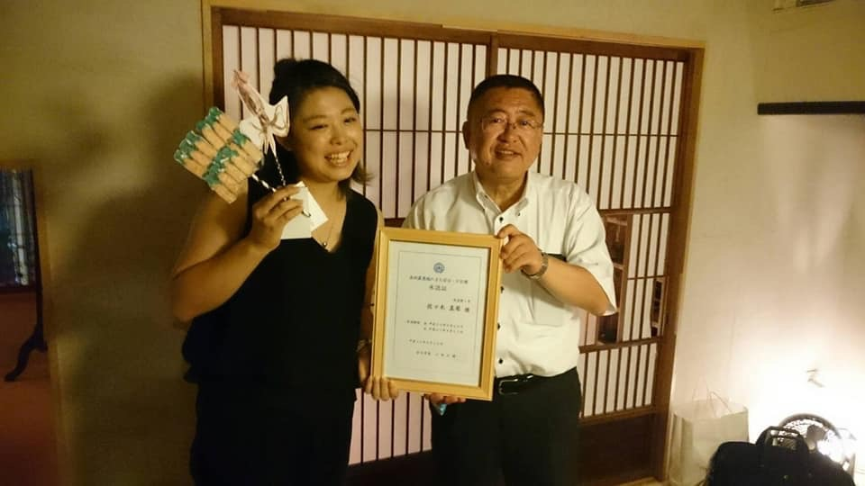 ふすまの前で額縁を一緒に持つ市長と女性の記念写真